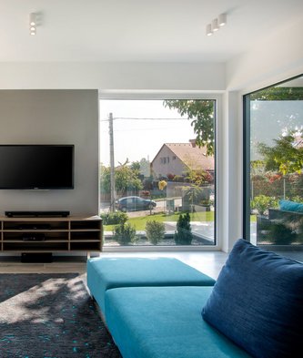 Modernes Haus mit Sonnenschutz vor den großen Glasflächen und Naturpool im Garten
