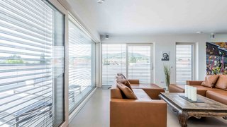 Wohnzimmer mit braunen Sofas und Tageslichtlenkung