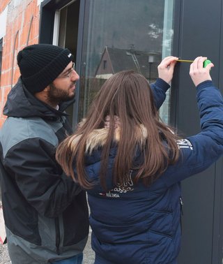 Lehrling misst mit Betreuer ein Fenster aus