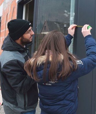 Lehrling misst mit Betreuer ein Fenster aus