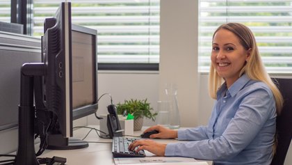 Mitarbeiter in blauem T-Shirt vor Monitor