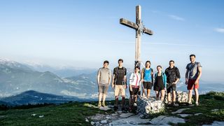 Gipfelkreuz Menschen an der Spitze vom Berg. Gipfelkreuz und Landschaft im Hintergrund.