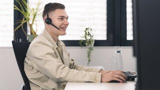 Person sitzt vor PC im Büro Person sitzt vor PC im Büro