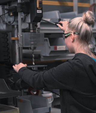 Mädchen mit Schutzbrille bei der Arbeit an einer Standbohrmaschine