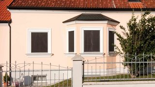 Beige Hausfassade mit geschlossenen Blinos Rollos