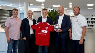 Gruppenfoto von Personen die Fußballdress und Fußball in den Händen halten.