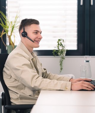 Person sitzt mit Headset vor dem Büro