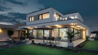 Sonnenschutz bei Nacht Modernes Haus bei Dämmerung mit Innenbeleuchtung und runtergelassenen Raffstoren