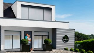 Haus mit Vorbaurollladen Personen stehen vorm Haus mit Vorbaurollläden