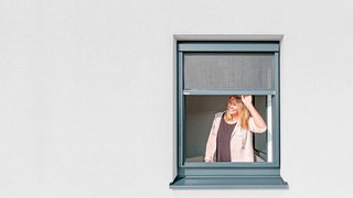 Blinos Rollo Aussenansicht Frau öffnet Blinos Rollo auf heller Fassade