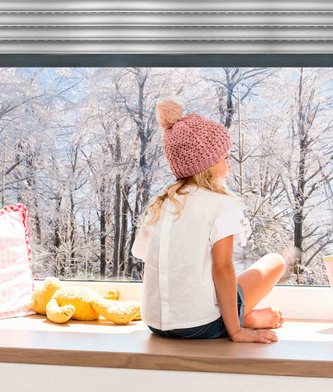 Mädchen vor Fenster mit Blick auf Winterlandschaft