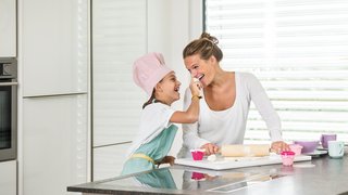 Mutter und Kind in der Küche beim Kuchen backen mit Raffstore im Hintergrund