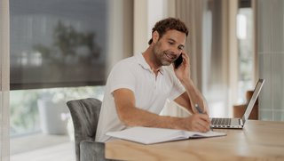 Mann arbeitet im Büro, im Hintergrund sieht man Sonnenschutz Sonnenschutz für das Büro