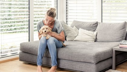 Frau und Hund sitzen im lichtdurchfluteten Wohnzimmer