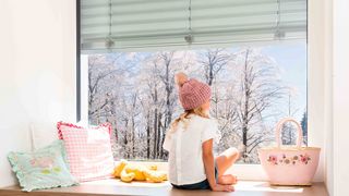 Sonnenschutz Klimaschutz Kind blickt durch Fenster auf Winterlandschaft